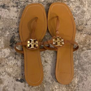 Tory Burch brown leather sandals with a gold emblem.